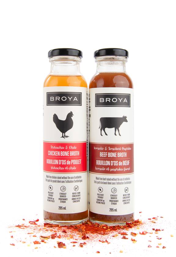 2 bottles of broth on a pile of spices in front of a white background.