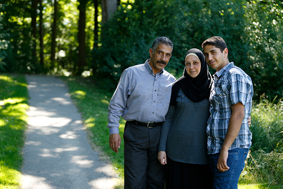 A Syrian-born family posing for a photo on a park trail.