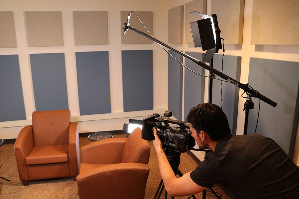 A cameraman setting up a camera for a studio recording.