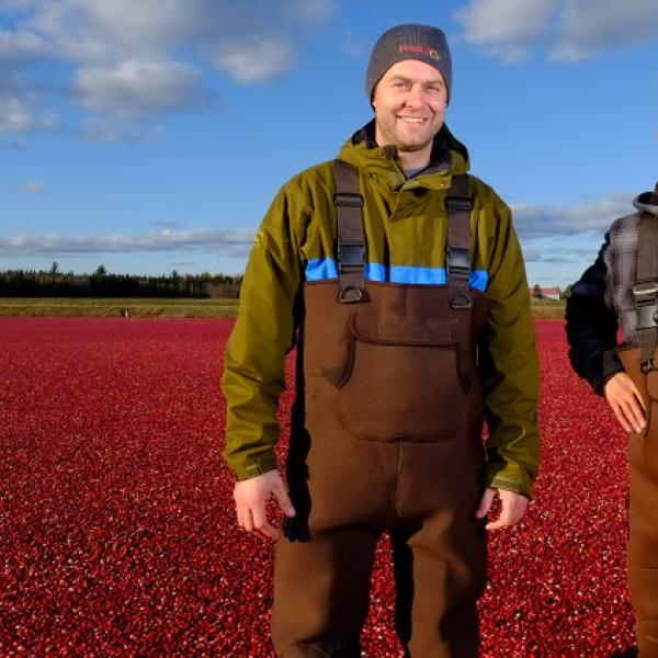 Crop scientist Simon Bonin and cranberry farmer Olivier Pilotte  posing for a photo in a field of cranberries.