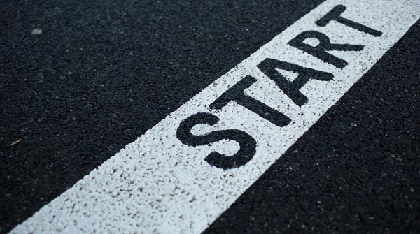 A close up photo of the start line on a running track. The track is black and the start line is white with the word "START" stenciled over it in black.