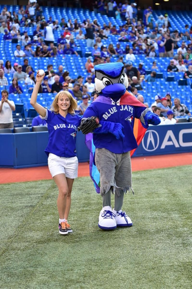 La chercheuse principale de l'article pose avec une mascotte sur un terrain de baseball.