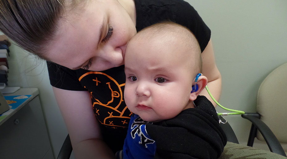 Close-up of a person holding and kissing a baby in a clinic.