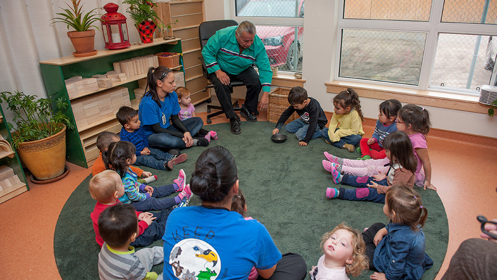 Elder Tacan leading a circle of children in a smudging ceremony.