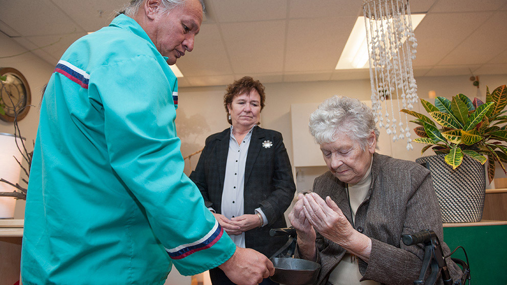 Elder Frank Tacan serves Elder Godmaire in a smudging ceremony.