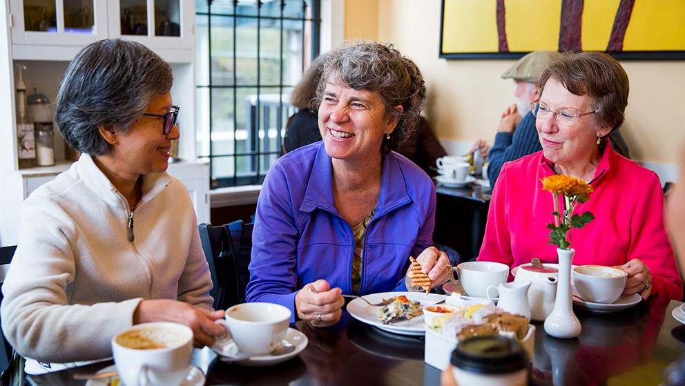 A group of women around a table discussing and eating.