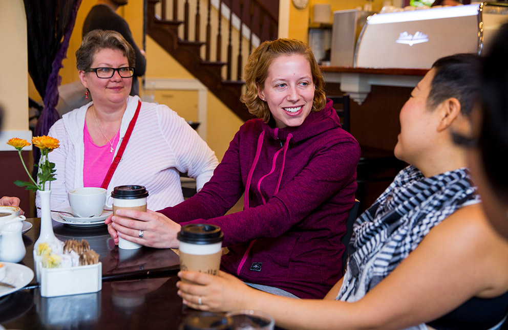 A group of women around a table discussing and eating.