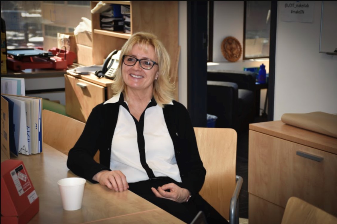 Janette Hughes seated at a wooden table with a coffee cup