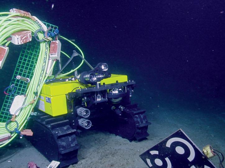 A robot with tank-like treads rolls along the ocean floor.