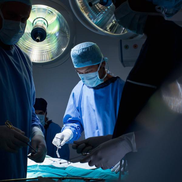 Several surgeons and nurses around an operating table.