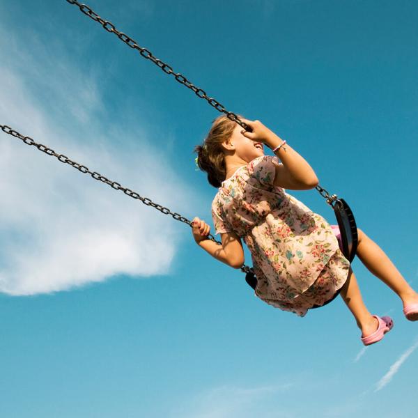 A child on a swing against a blue sky.
