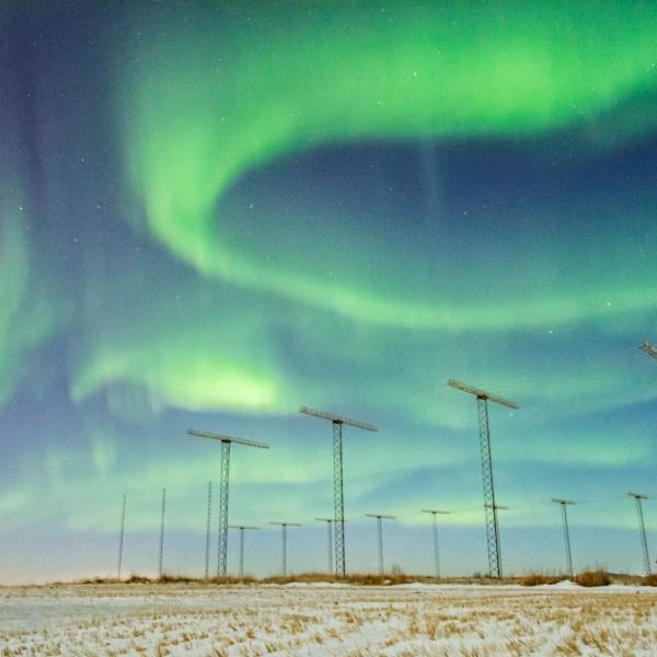 SuperDARN antennas with aurora borealis in the sky above.