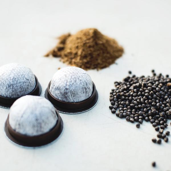 Three small piles of coffee beans, coffee grounds and coffee pods on a white background