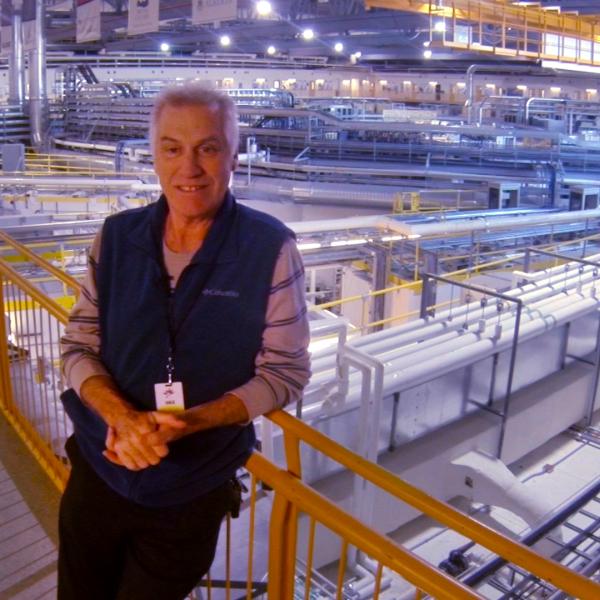 Tour guide and taxi driver, Bill Baker, poses in front of the synchrotron beamlines inside the Canadian Light Source