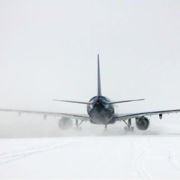 An airplane viewed from the rear on snowy ground.