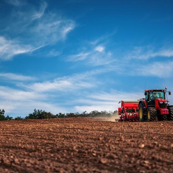 A tractor riding over a barren field.