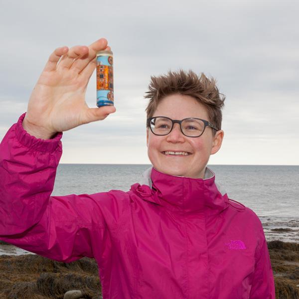 Dr. Franziska Broell holding a small container in front of an ocean view.
