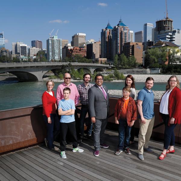 A group of citizens posing for a photo in front of a city landscape.