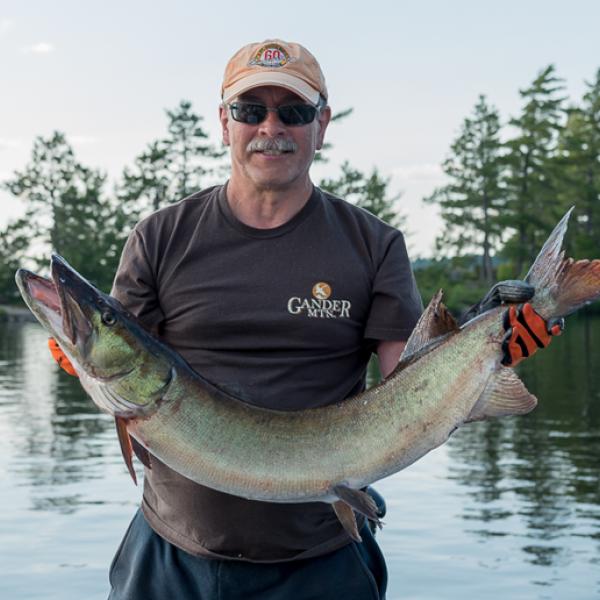 Image of Regan Thompson holding a fish with his two arms.