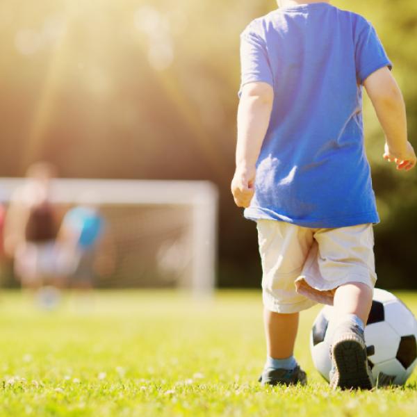A child kicking a soccer ball toward a net