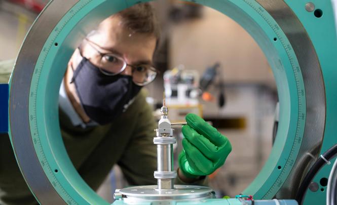 A person viewed through a green circular machine manipulates a small device