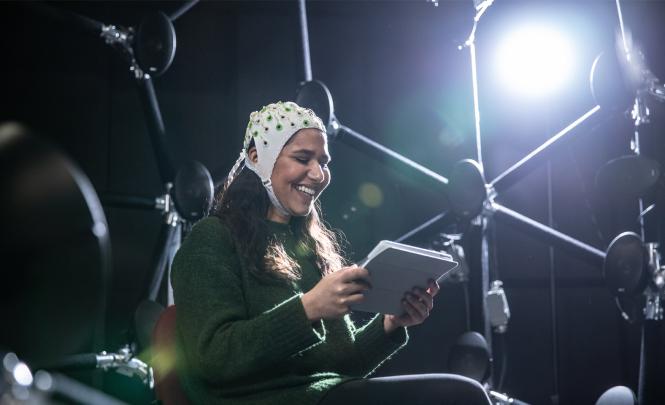 A person wearing a headpiece with sensors surrounded by a network of speakers