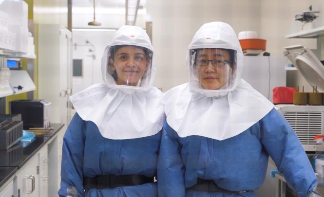 Photo of two women researchers wearing personal protective equipment in a lab