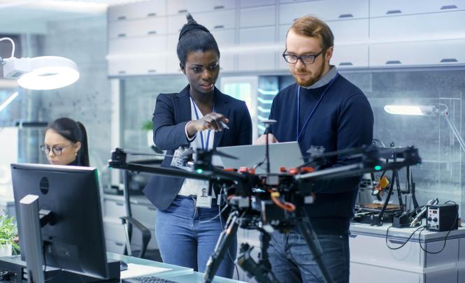 A group of researchers studying a drone in a laboratory.