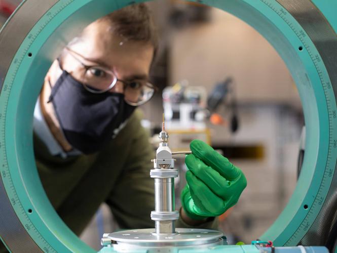 A person viewed through a green circular machine manipulates a small device
