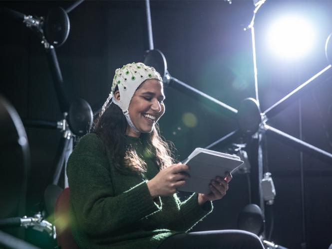 A person wearing a headpiece with sensors surrounded by a network of speakers