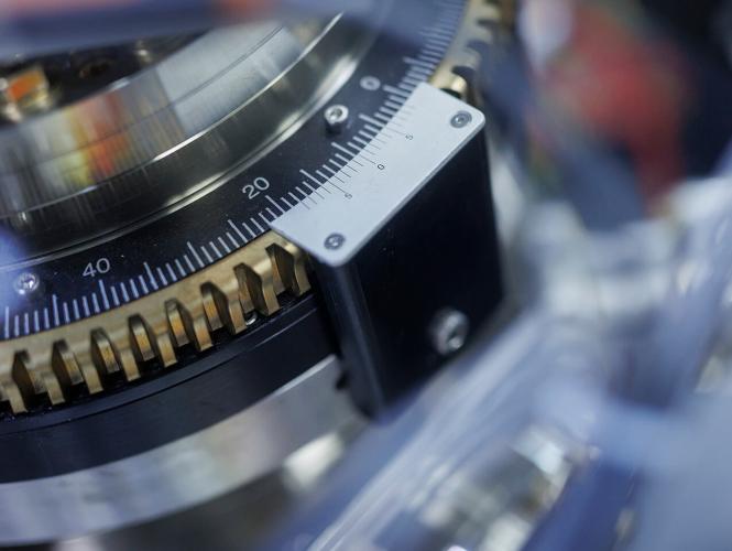 Une personne se tennant derrière un appareil en forme de cercle et ajuste une pièce d'équipement métallique.