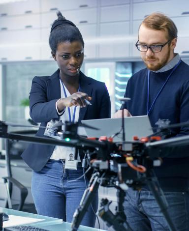 A group of researchers studying a drone in a laboratory.