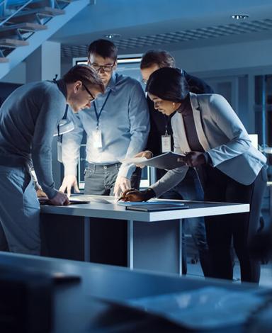 A group of people in discussion standing around a table