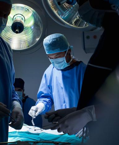 Several surgeons and nurses around an operating table.