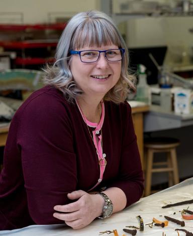 Lisa Rankin leaning on a lab bench covered with artifacts.