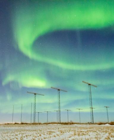 SuperDARN antennas with aurora borealis in the sky above.