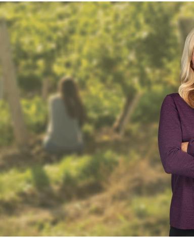 Heidi Fielding poses in front of a blurred image of a vineyard in the background