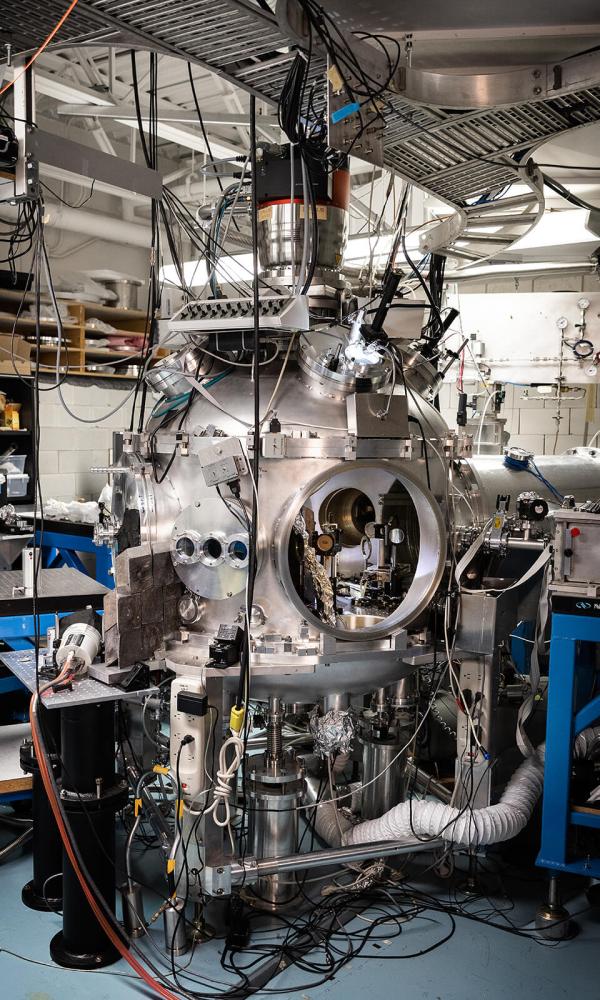 A large, complicated machine with many wires and tubes sits in a lab.