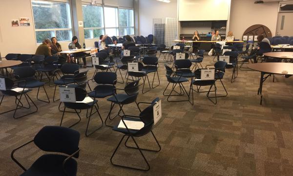 Une grande salle de conférence où des chaises sont disposées en petits cercles.