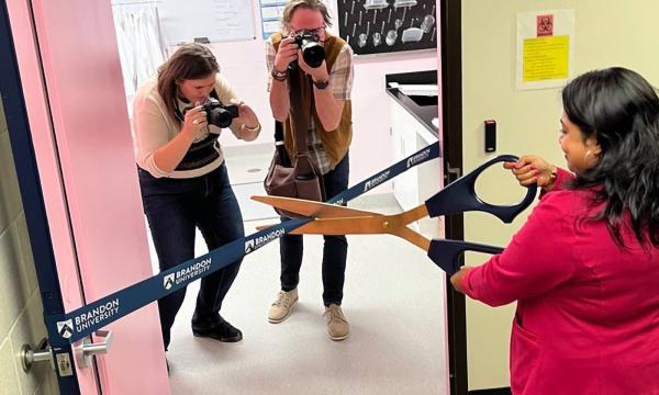 Des photographes immortalisent le moment de la cérémonie d’inauguration du laboratoire où Mousumi Majumder coupe le ruban à l’aide d’une géante paire de ciseaux.