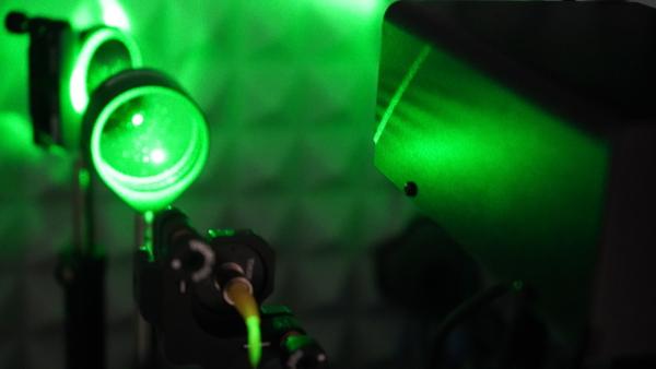 A green laser beam directed at a super-resolution microscope.