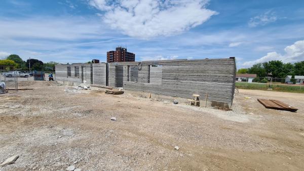 The cement walls of a partially built building viewed from the side.