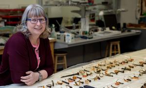 Lisa Rankin est appuyée sur un comptoir de laboratoire jonché d’artefacts archéologiques.