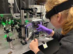 A researcher wearing protective laser goggles inserts an ore sample into a chamber that is probed by green laser light.