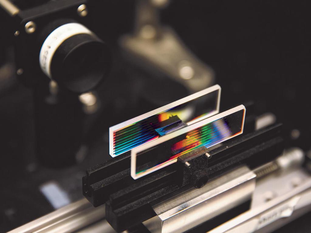 An apparatus holds two small rectangular glass slides with coloured lines.