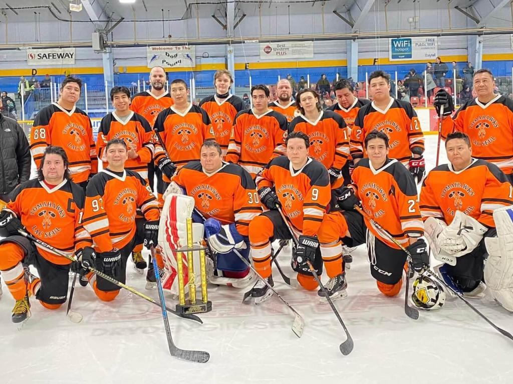 Une équipe de hockey en maillots orange pose sur la glace de l'aréna. 