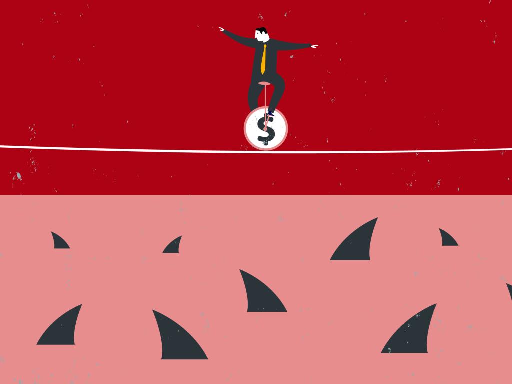 Illustration of a man in a grey suit sitting on a unicycle with a dollar sign on it. He is balancing on a tightrope and looking down at the shark fins darting out of the water below. The sharks are waiting for him to fall.