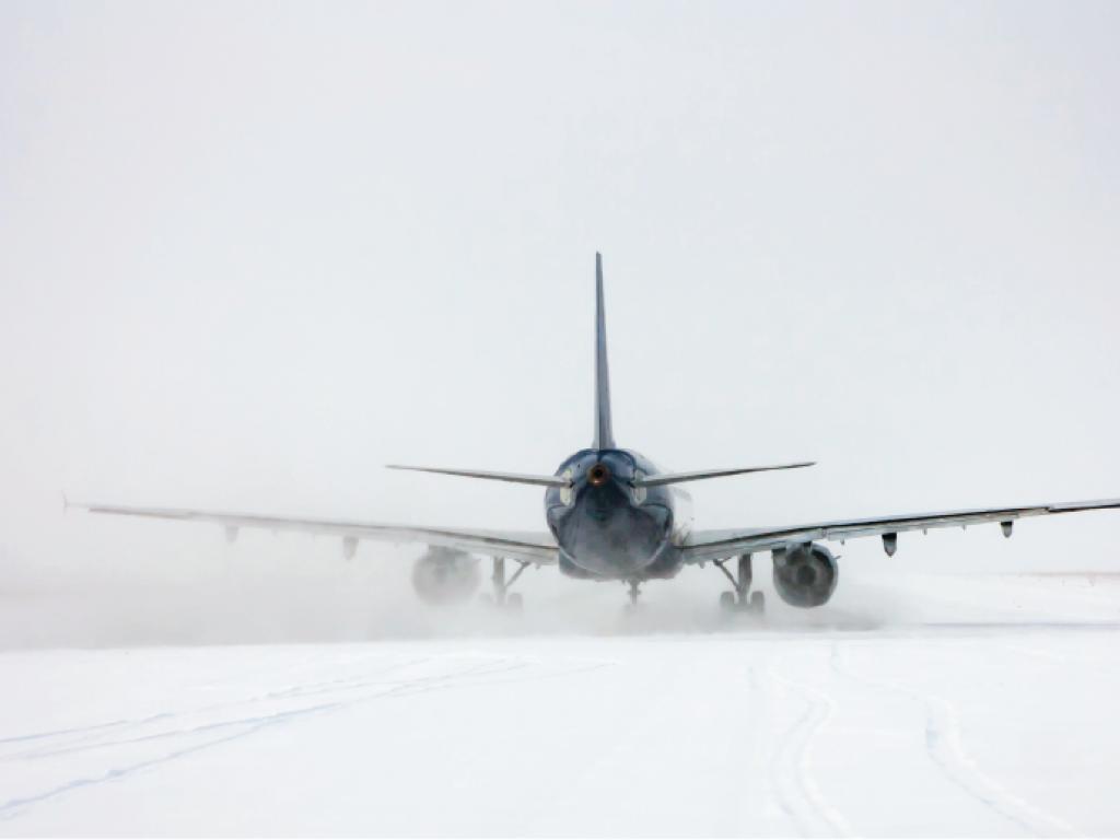 An airplane viewed from the rear on snowy ground.