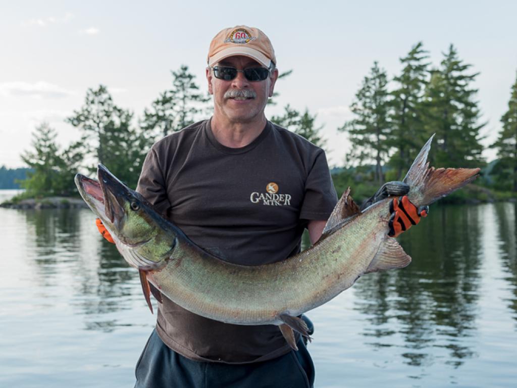 Image of Regan Thompson holding a fish with his two arms.