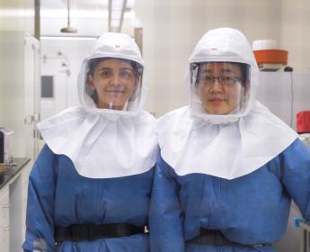Photo of two women researchers wearing personal protective equipment in a lab